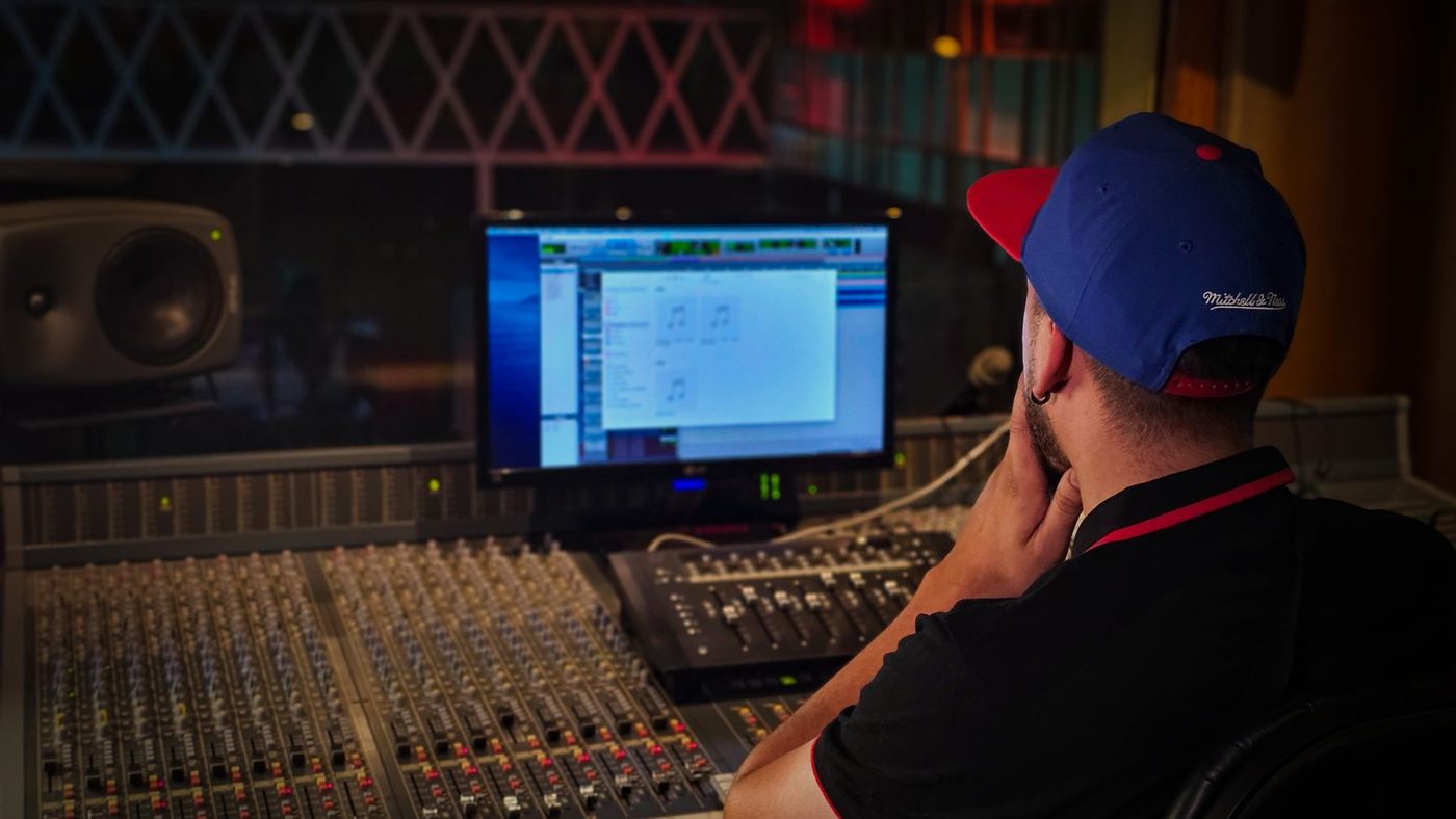 Audio engineer working at mixing console in cozy recording studio with ambient lighting.