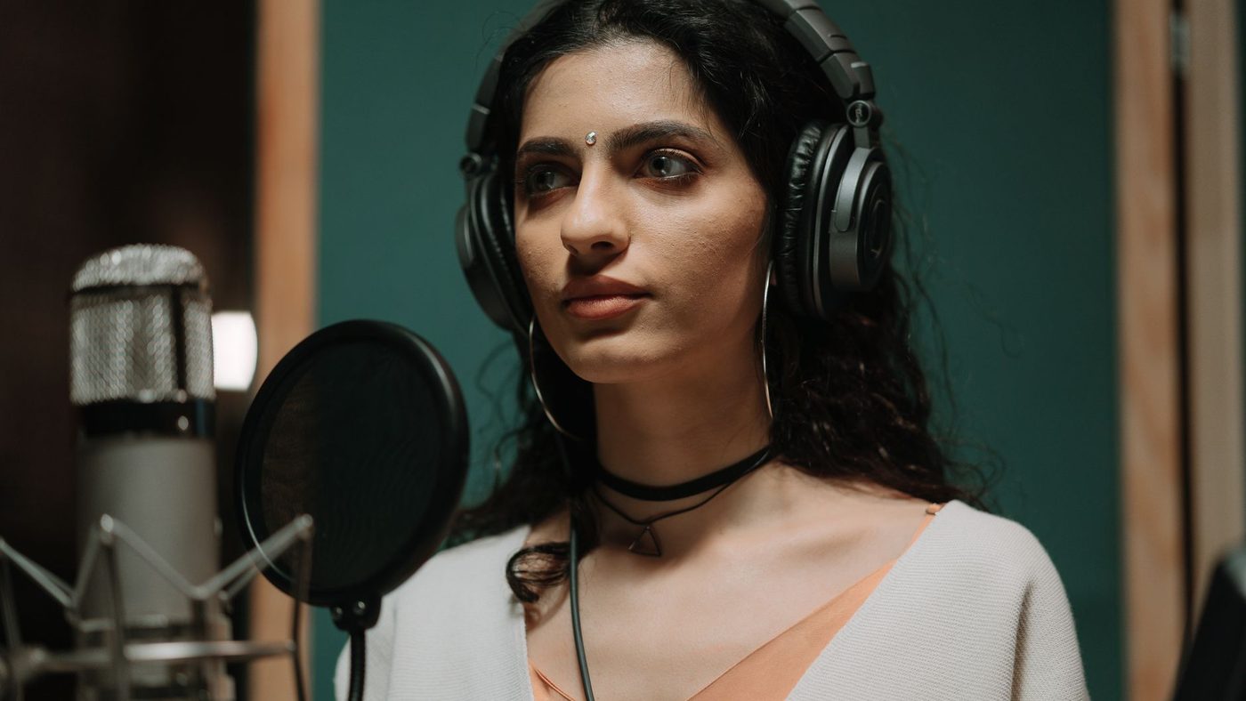 Female singer recording vocals in a professional music studio wearing headphones.